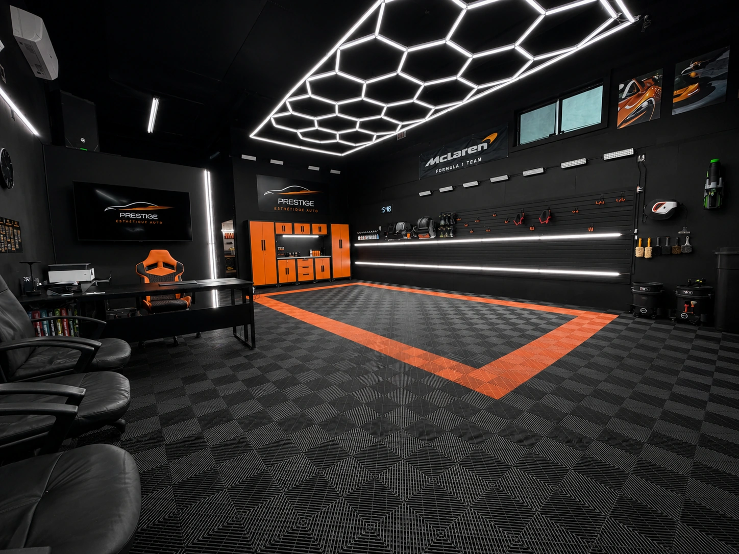 Atelier Prestige Esthétique Auto : baie de détaillage noire, plafond LED hexagonal, armoires orange