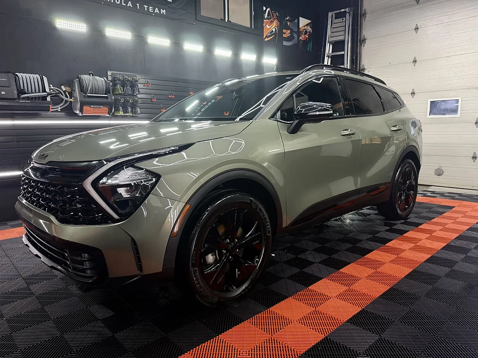 SUV vert sauge sous l'éclairage LED d'un atelier de détaillage professionnel